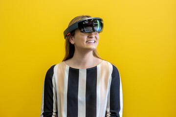 Young woman wearing a virtual reality device, viewing a virtual world in augmented reality. Depreciated virtual device, augmented reality visualisation. Head-mounted display to see a digital land