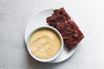 Overhead view of Nigerian kilishi and yellow garri on a white plate, top view of garri and nigerian spicy beef jerky, flatlay of cassava granuls and dried beef suya