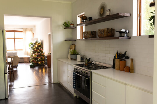 Cozy kitchen leading to living room with Christmas tree and festive decor, at home