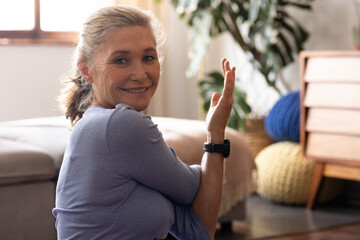 Smiling senior woman at home enjoying peaceful moment in cozy living room