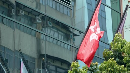 Closeup of the Hong Kong flag fluttering against a modern glass building, highlighting cultural pride and the urban environment in HongKong.