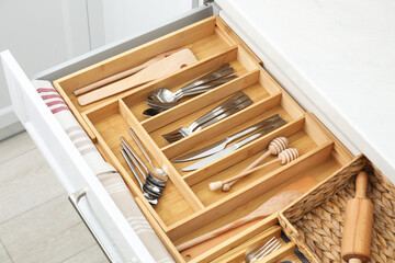 Box with cutlery in drawer, closeup. Kitchen utensils storage