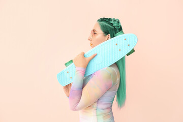Beautiful woman with long hair and skateboard on color background