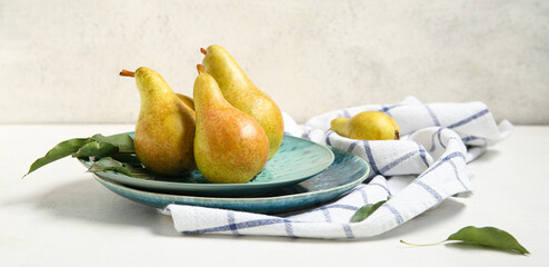 Plates with ripe pears on white background