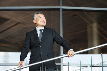 Portrait of Asian senior businessman walking in the office building.