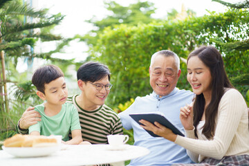 Multi generation Asian family relaxing in backyard garden together.
