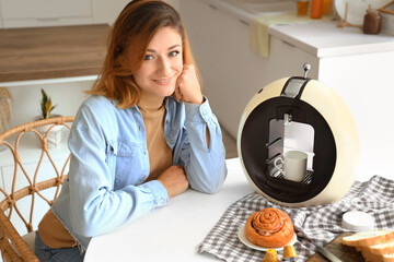 Young woman with coffee machine in kitchen