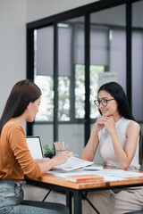 Fototapeta premium Two women discussing business strategies in a contemporary office setting, showcasing teamwork and collaboration.