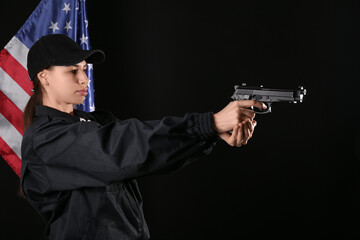 Female police officer with gun and flag of USA on dark background