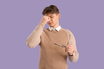 Young man suffering from headache on lilac background