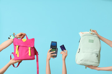 Female hands with different backpacks, school supplies, credit card and payment terminal on blue...