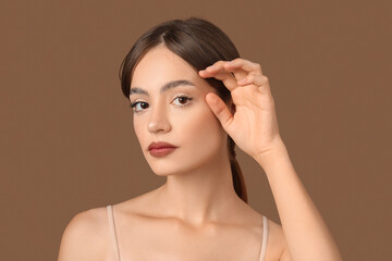 Obraz premium Young woman with beautiful eyebrows on brown background