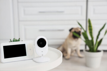 CCTV camera with video monitor on table against pug dog in kitchen, closeup