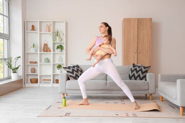 Fototapeta premium Sporty young woman with her little baby doing yoga at home