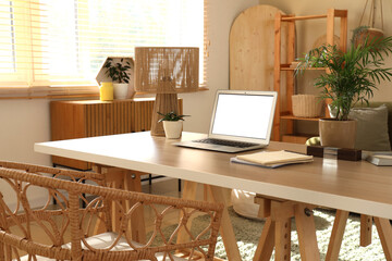 Programmer's desk with laptop, lamp and plants in living room