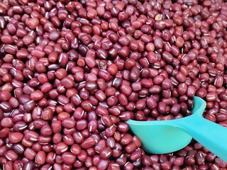 A close-up view reveals vibrant red beans nestled together with a white scope, their glossy surfaces reflecting light and hinting at the delicious dish they will soon become.
