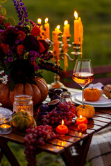 Fall table decoration with pumpkins, wine, candles. Family cozy thanksgiving dinner arrangement outdoors, wedding elegant decor. Countryside style, simple handmade setting, autumn mood, inspiration