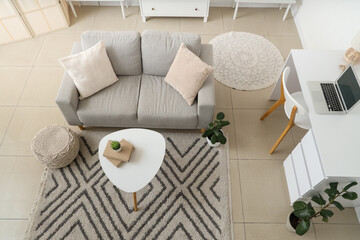 Interior of living room with grey sofa, table and workplace