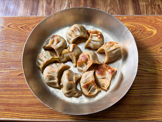 A plate of dumplings sits on a wooden table
