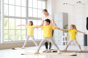 Cute little children with coach training on mats in gym