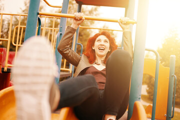 A joyful woman sliding down a colorful playground slide, embodying bliss and happiness in the warm sun
