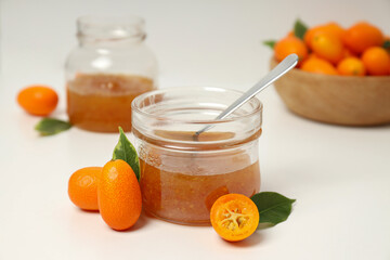 Kumquat fruits in bowl and glass jars with jam on white background