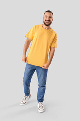 Fototapeta premium Young man in yellow t-shirt on light background
