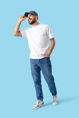 Naklejka premium Young man in cap and white t-shirt on blue background