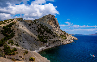 Rocks and mountains on the seashore against the background of clouds.