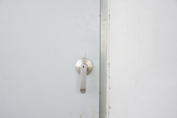 Close-up of a door handle. The door handle is made of metal and has a modern, sleek design. The handle is attached to the door and appears to be made of a smooth, light-colored material.