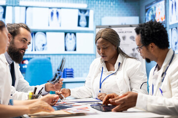 Doctors at a treatment center in a meeting to review healthcare records and x ray scans. Licensed...