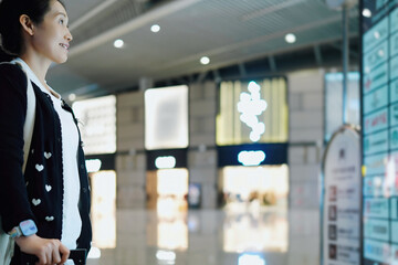 Excited Traveler at Airport Terminal Looking Towards Departure Board