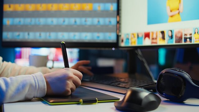 Photo editor using graphic tablet to edit color balance, delivering appealing photographs for magazines. Close up on graphic designer using stylus on touchscreen device to modify images, camera B