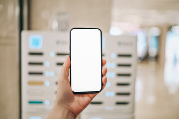 Modern Technology in Action: Hand Holding a Blank Smartphone in a Vending Environment