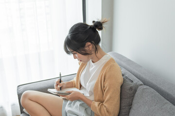 Asian Business woman working from office taking reading and writing notes in note pad