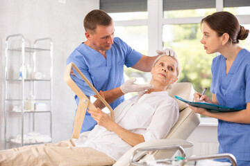 Obraz premium Beautician talking with patient before injection treatment, while client observing herself in mirror.