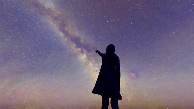 Children standing on the top of the mountain looking up at the stars and exploring the universe