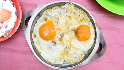 Sunny-side up egg on a frying pan. Delicious fried egg, Banh mi chao. Fried eggs in a frying pan. Vietnam street food.