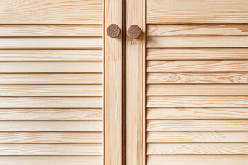 Wooden louvered doors with wooden knob handles close-up. Louvered doors of outdoor kitchen are made from light pine wood with natural grain pattern