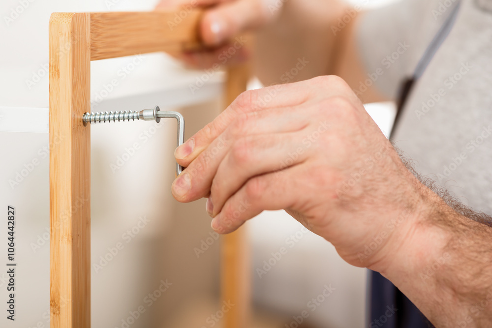 Aufkleber closeup of unrecognizable carpenter's hands while he tightening screws working assembling shelf indo