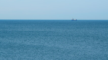 Fishing Boat On The Horizon At Sea. Abstract Small Waves On Calm Water Surface In Motion. Real time. © artifex.orlova