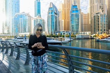 Happy beautiful tourist woman with smartphone enjoying vacation in Dubai in United Arab Emirates.