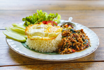 Stir-fried pork and basil leaves with rice and a fried egg served with fresh vegtetables and fish...