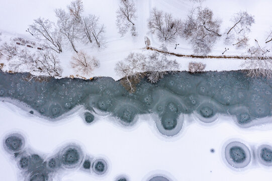 winter park landscape with snow-covered riverbank and freezing river. aerial drone view.