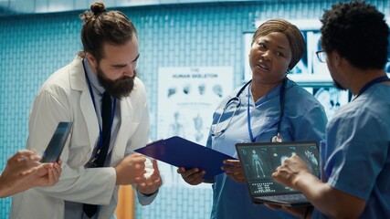 Medical professionals review x ray results and discuss patient care strategies during a meeting. Team of licensed healthcare experts working to provide accurate diagnosis in a clinic. Camera A.