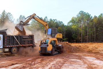 An excavator is used to load earth into dump truck on construction site.