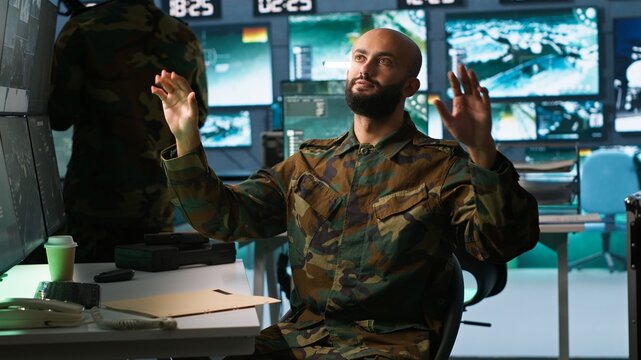 Military agent using augmented reality tech in control room, analyzing aerial reconnaissance data. Intelligence corps expert controlling drones attacking strategic targets using AR hologram, camera A