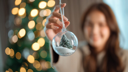 Closeup hand of woman hold Christmas balls present decorate Christmas tree at home, Merry Christmas and Happy New Year.