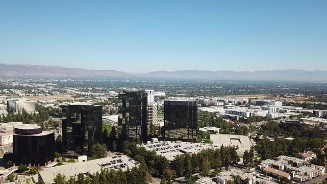 Aerial backwards shot of AIG Capital Service Towers in Woodland Hills District, of LA, USA. Sunny day over american neighborhood and mountains in background.