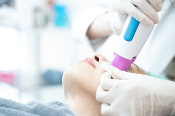 Beautician doing laser rejuvenation on woman face. Facial skin care.